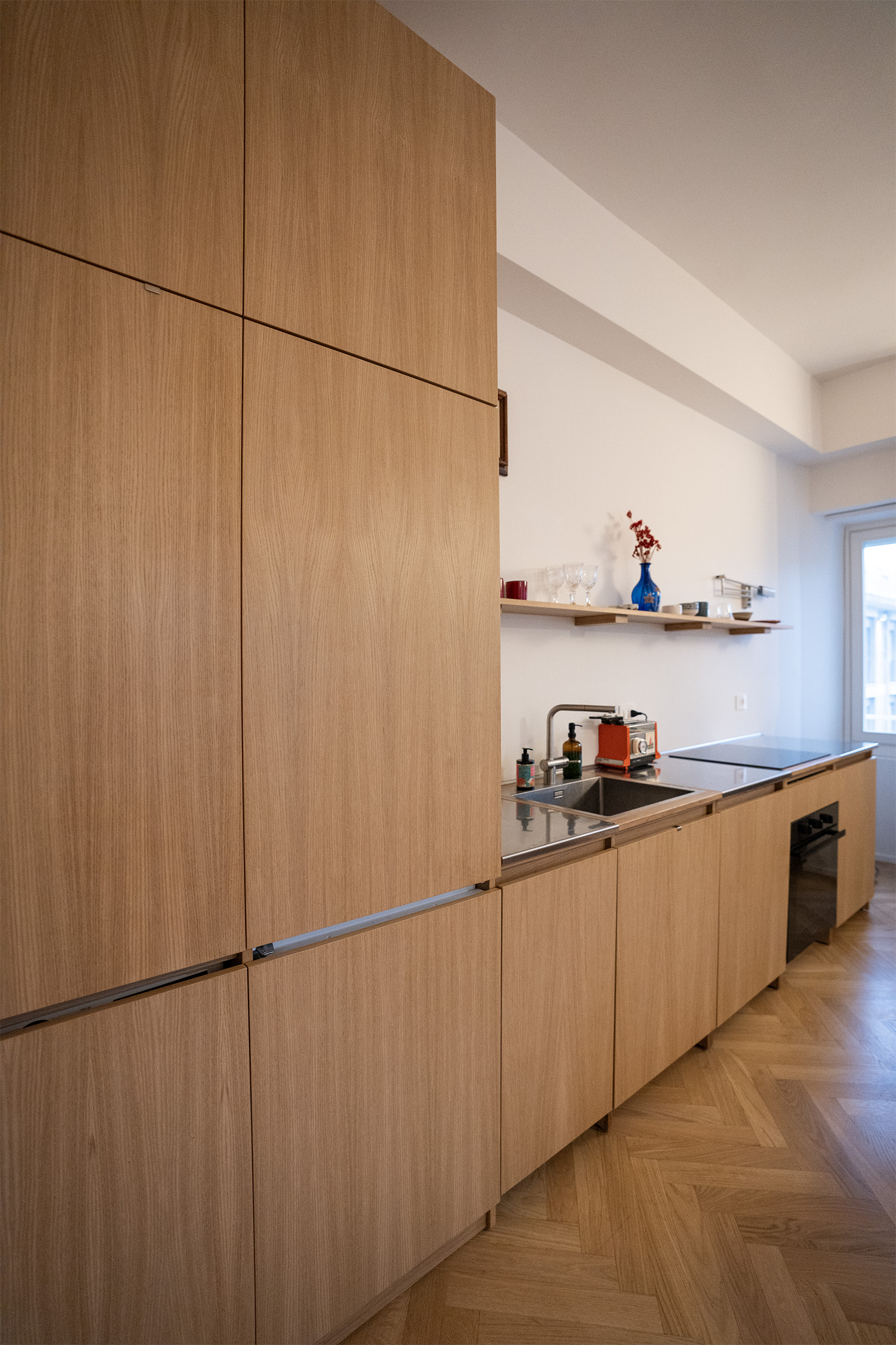Cucina lineare in rovere con colonne frigo e lavastoviglie integrate