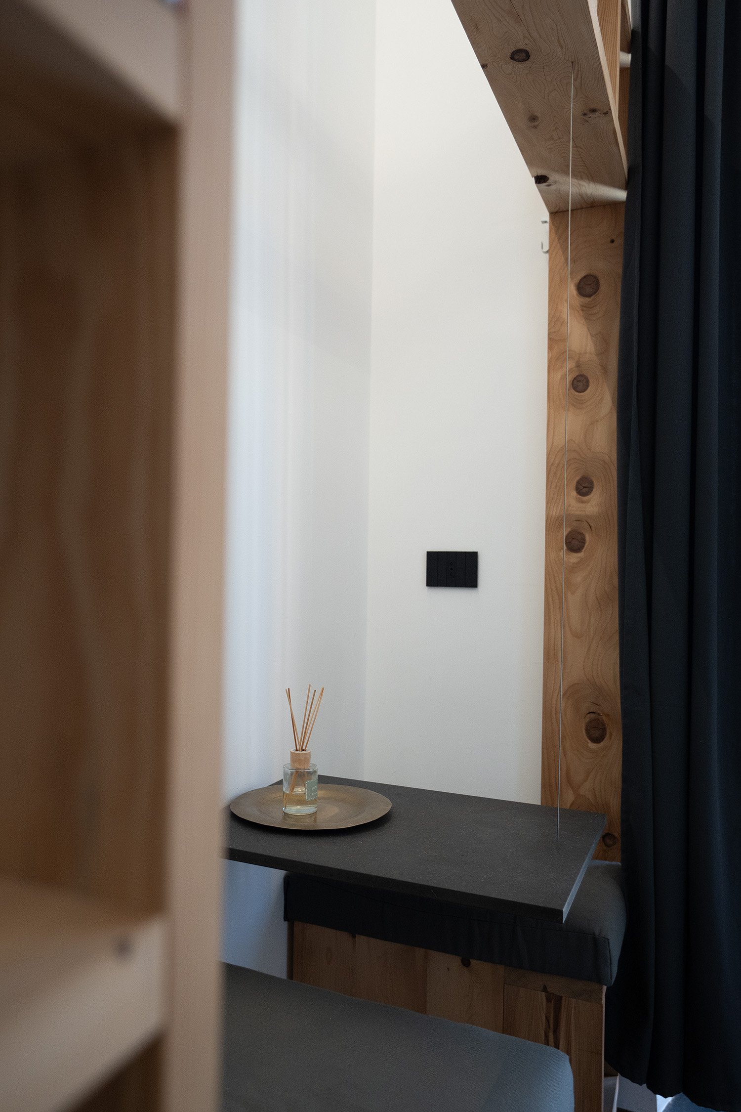Dettaglio della seduta d’ingresso con tavolino in Valchromat nero e struttura in legno