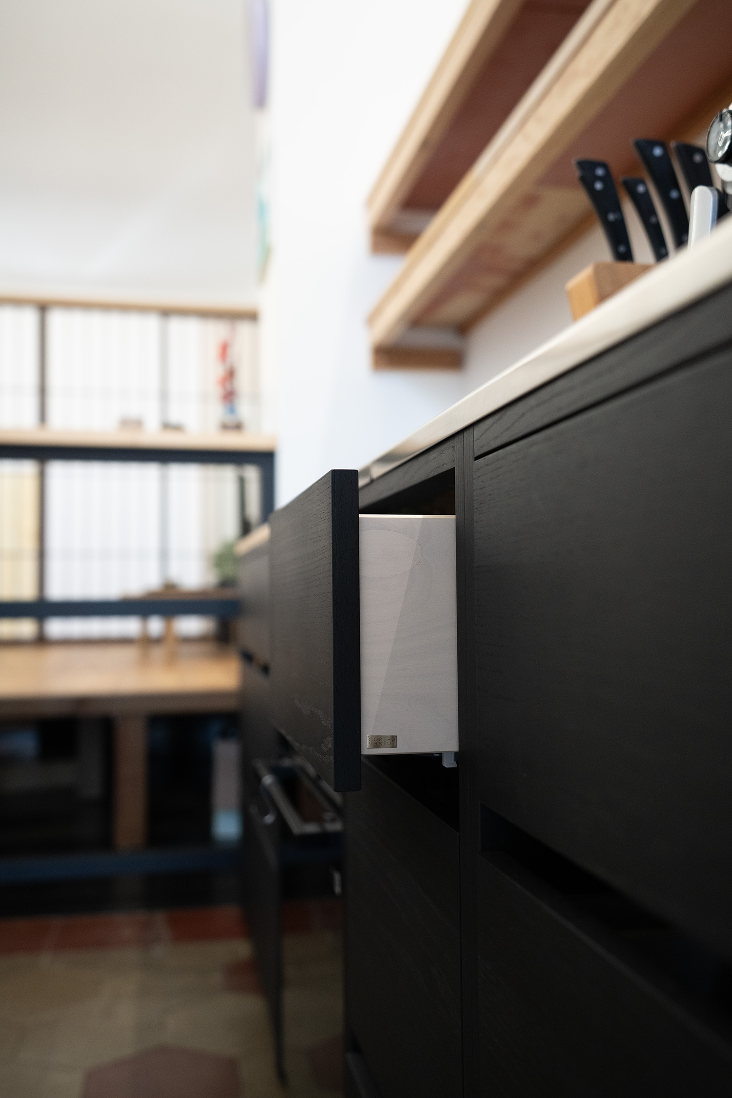 Basi nere per la cucina su misura,  piano in legno, apertura cassetto e piattaforma sullo sfondo